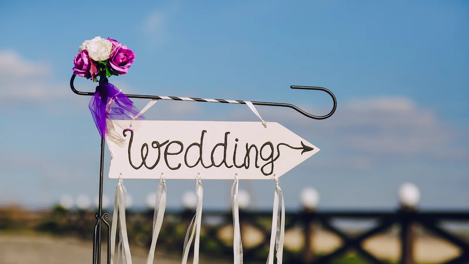 A wedding direction sign decorated with flowers and ribbons